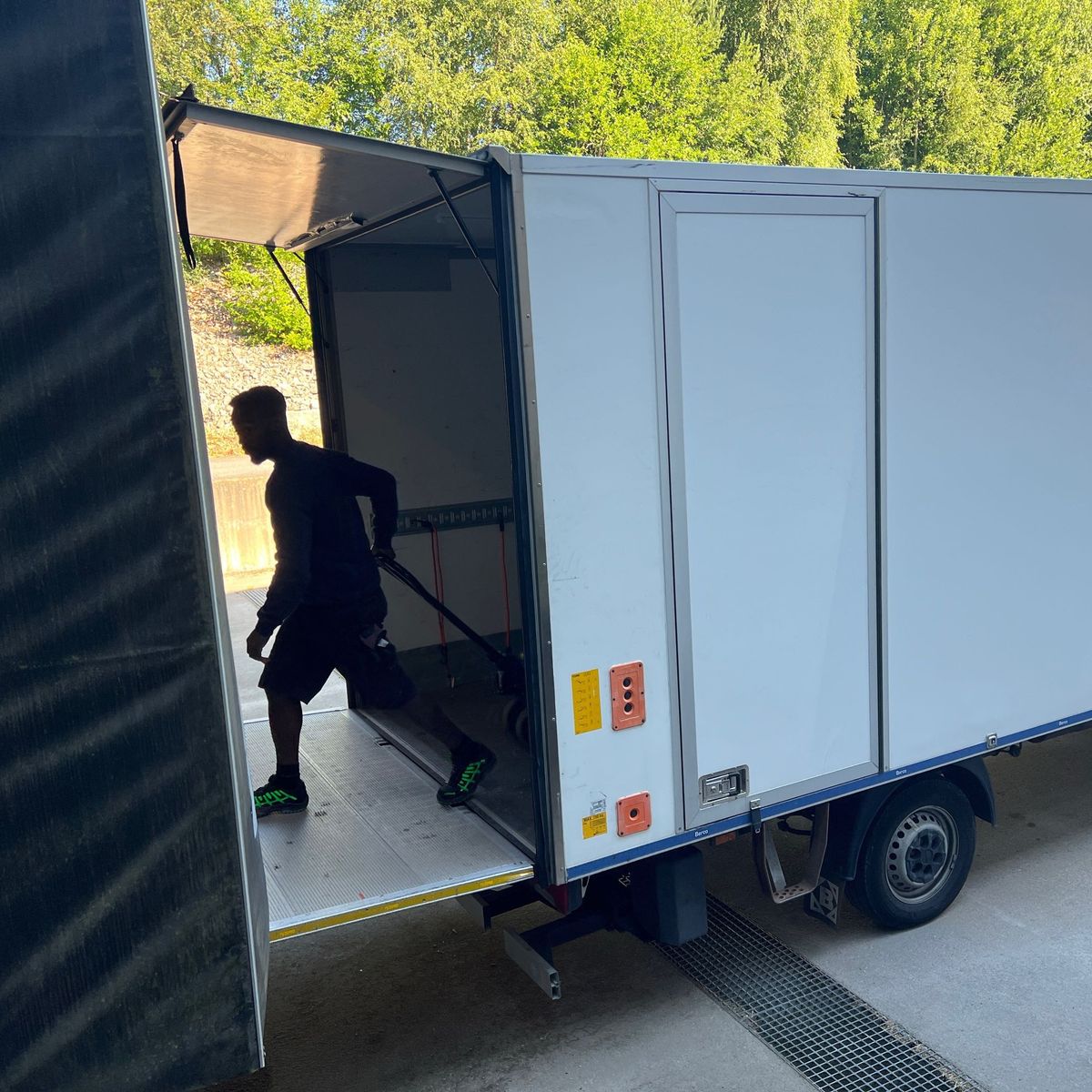 Bilen til Indoro Transport med løftelemmen nede, sjåføren triller en pallejekk inn